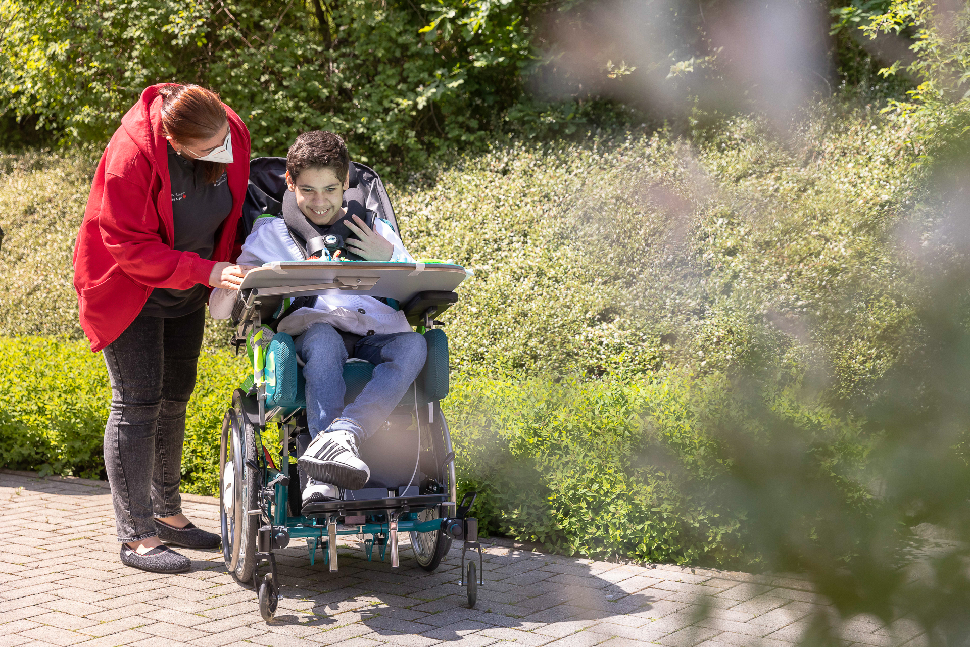 Pflegefachkraft hilft Kind im Rollstuhl